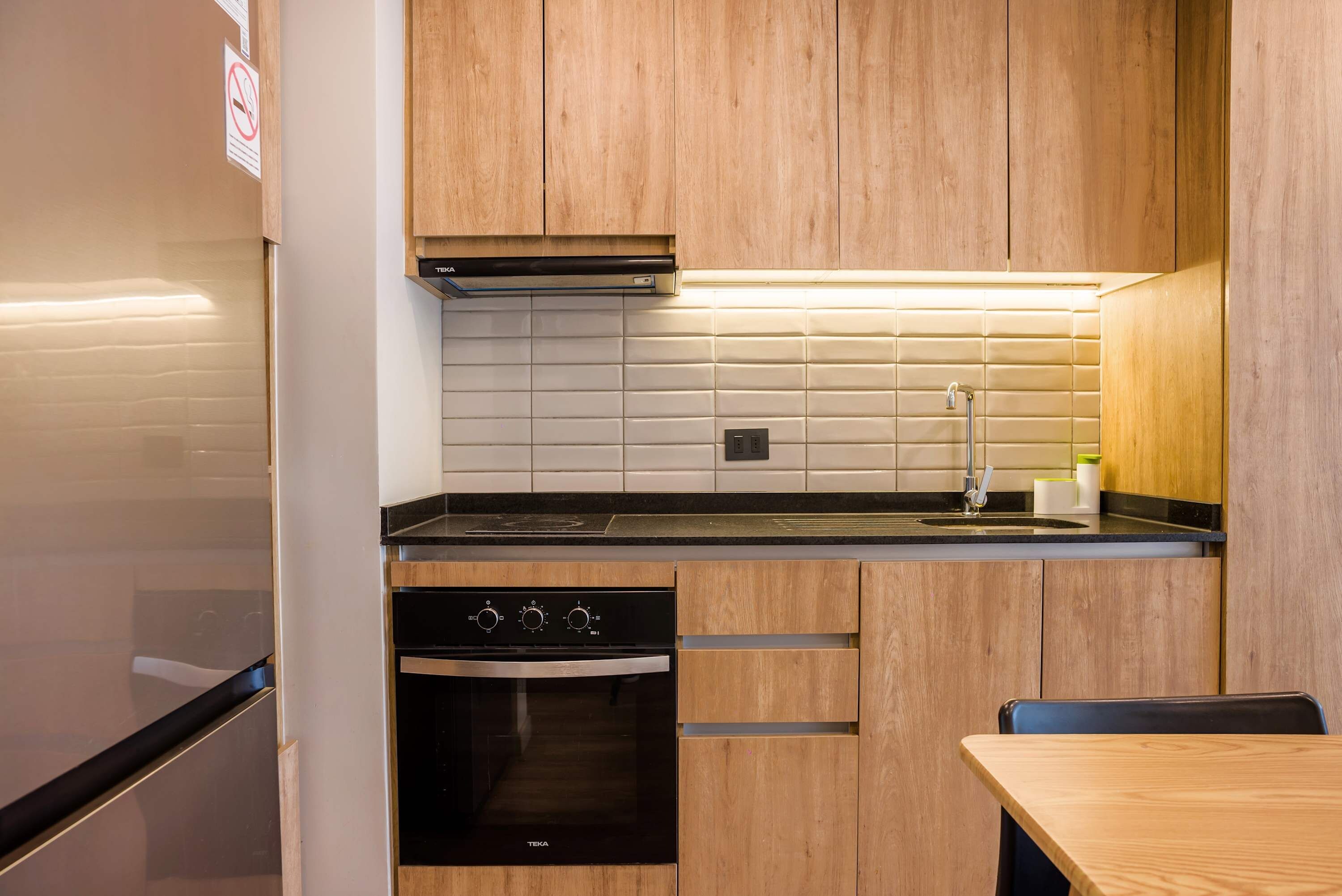 Una cocina moderna con armarios de madera, un horno negro y un lavamanos de acero inoxidable.