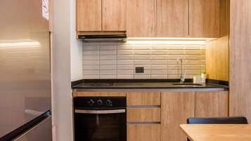 Una cocina moderna con armarios de madera, un horno negro y un lavamanos de acero inoxidable.