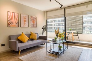 A modern living room with a grey sofa, a glass coffee table, and artwork on the wall. - Family Adventure Charming 2BR In Providencia For 5 (Providencia)