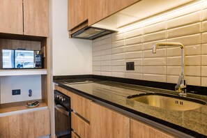 A modern kitchen with wooden cabinets, a stainless steel sink, and a built-in oven. - Family Adventure Charming 2BR In Providencia For 5 (Providencia)