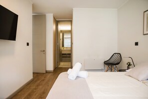 A hotel room with a bed, a chair, a television, and a bathroom visible through an open door. - Family Adventure Charming 2BR In Providencia For 5 (Providencia)
