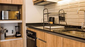 Una cocina moderna con armarios de madera, microondas integrado, horno doble y encimera negra.
