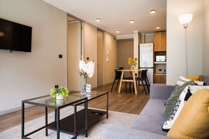 Living room with a comfortable gray sectional, glass coffee tables, and an adjoining dining area with four seats. - Family Adventure Charming 2BR In Providencia For 5 (Providencia)