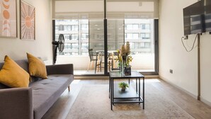 Una sala de estar moderna con un sofá, una mesa de centro y un televisor montado en la pared.