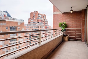 A balcony with a potted plant, a hanging light fixture, and a view of surrounding buildings.