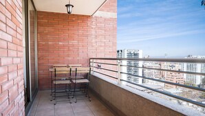 A balcony with a brick wall, metal railing, and a view of buildings. - Cozy Apartment Perfect for Families and Long Stays (Las Condes)