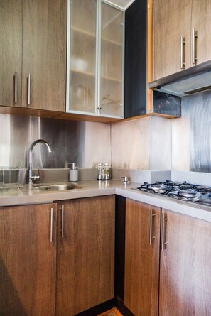 Une cuisine avec des meubles en bois, un évier en acier inoxydable et une cuisinière à gaz.