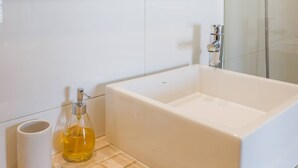 A modern bathroom with a bathtub, a glass shower enclosure, and a mirror above the sink. - Cozy Apartment Perfect for Families and Long Stays (Las Condes)