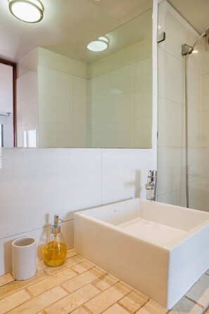 A modern bathroom with a bathtub, a glass shower enclosure, and a mirror above the sink. - Cozy Apartment Perfect for Families and Long Stays (Las Condes)