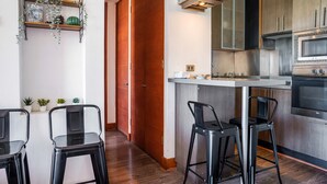 Eine moderne Küche mit Edelstahlgeräten, einer Holztür und einer Bar mit Hockern.