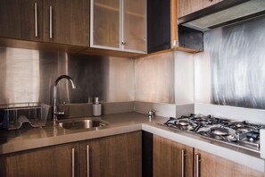 Une cuisine équipée d’appareils électroménagers en acier inoxydable, de meubles en bois et d’une cuisinière à gaz.
