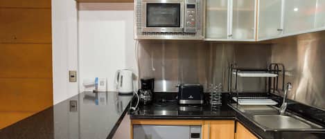 A compact kitchen with a microwave, coffee maker, toaster, and a dishwasher.