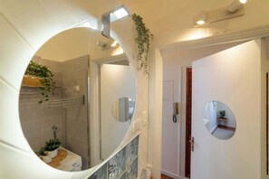 A bathroom with a shower, a toilet, a mirror, and a plant. - Chic Urban Home in Santiago | Relax and Unwind (Providencia)