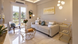 A modern living room with a sofa, coffee table, and a gold-framed side table. - Gold Apartment (Nea Smirni)
