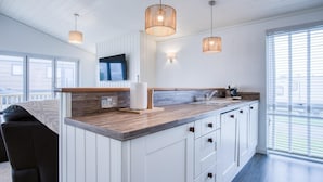 Een moderne keuken met witte kasten, een houten aanrechtblad en hangende lampen.