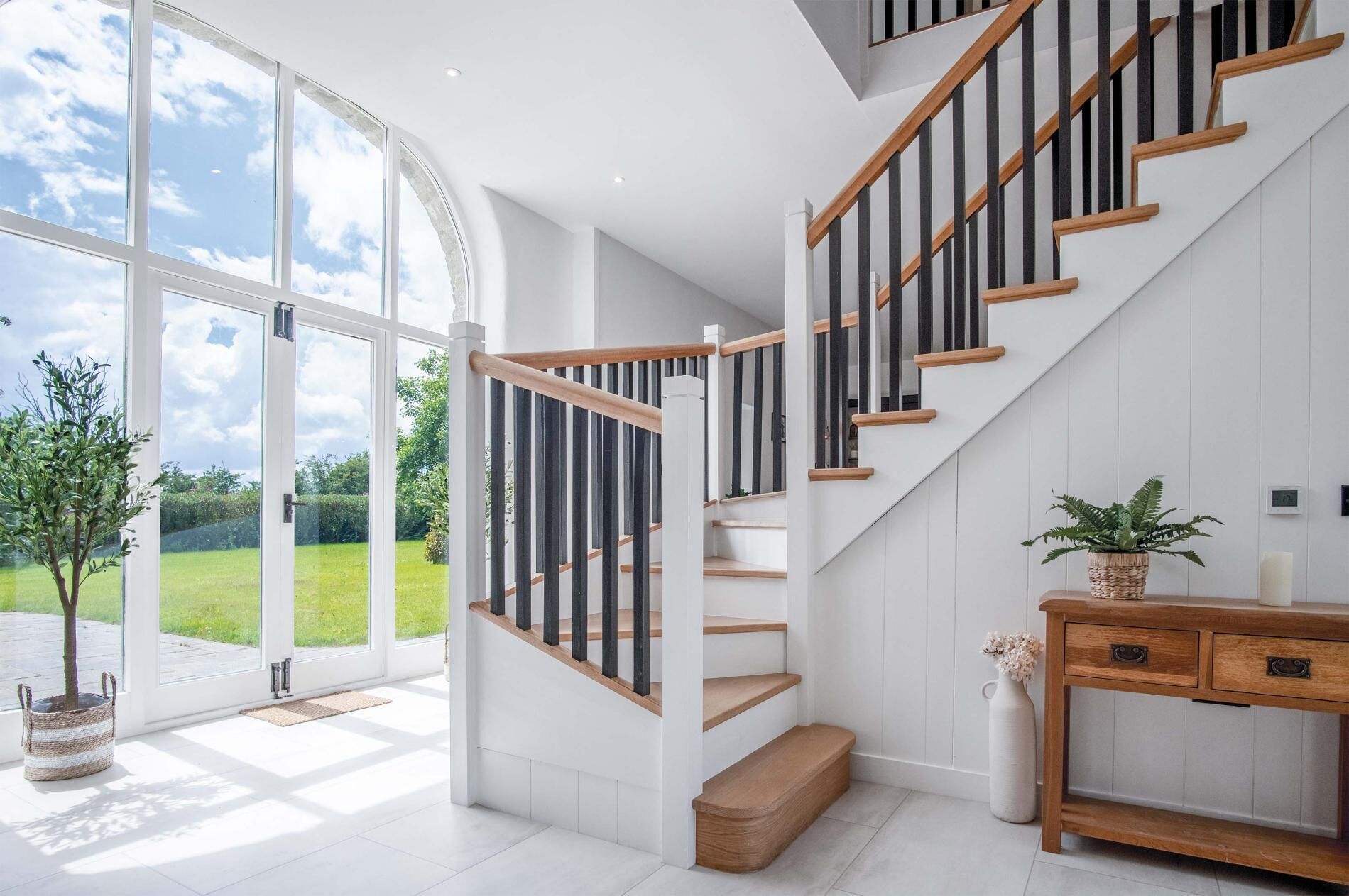 Un escalier moderne avec des marches en bois et des balustrades noires, menant à l’étage supérieur.