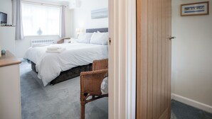 A hotel room with a bed, a chair, a TV, and a window with curtains. - Clover Cottage - 2 Bedroom Cottage - Begelly (Kilgetty)