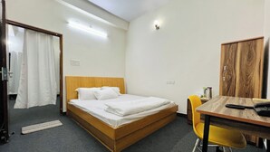 Una cama individual con cabecera de madera, una mesita con una silla y un armario.