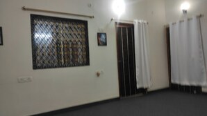 Una habitación con ventana, puerta y cortina.