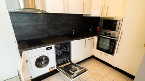 Eine kompakte Küche mit Geschirrspüler, Backofen und integriertem Mikrowellenherd.