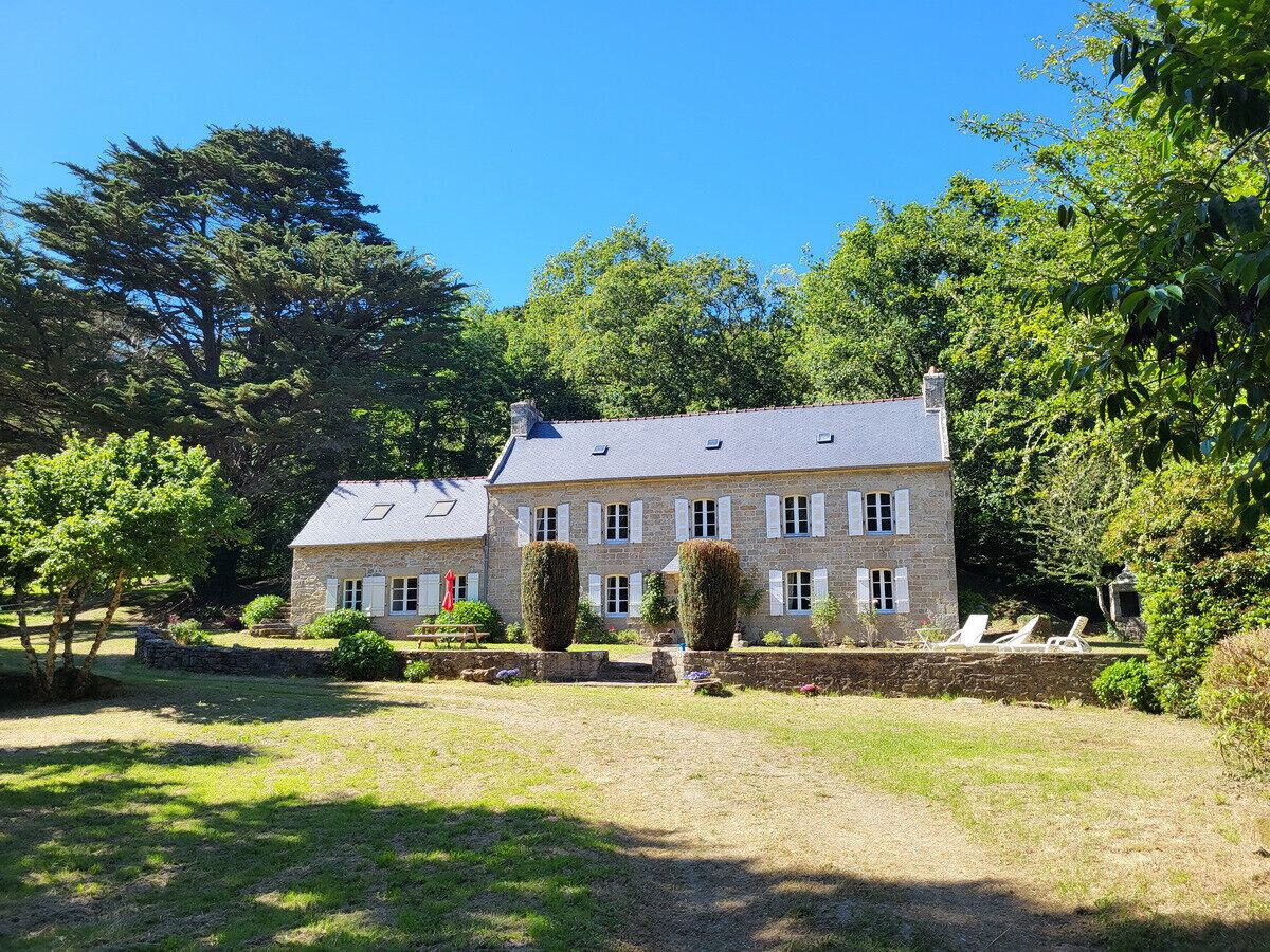 A stone building with a symmetrical facade, multiple windows, and a well-maintained lawn with a few trees.