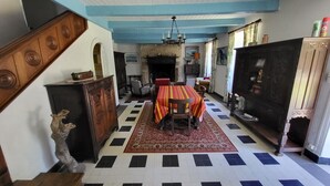 Un coin repas avec une table dressée pour quatre personnes, une cheminée et un escalier menant à une autre pièce.