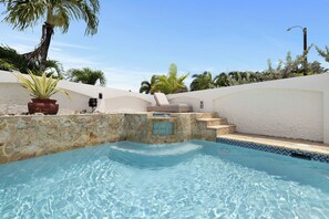 A swimming pool with a stone edge, a small window, and steps leading into the water. - Enchanted Sunrise | Fun and Spacious w. Pool (Dorado)