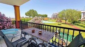Ein Balkon mit Tisch und Stühlen, der auf einen gepflegten Garten und einen Pool mit Blick blickt.
