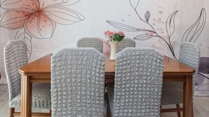 Et spisebord med seks stole, hver dækket med et stof med struktur. En vase med blomster står på bordet.