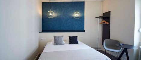 Une chambre d’hôtel avec un grand lit, deux tables de chevet, une chaise, un bureau et une armoire.