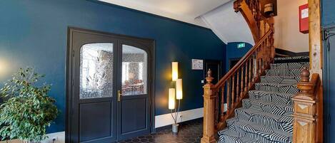 A staircase with a patterned carpet leading to a door with frosted glass panels.