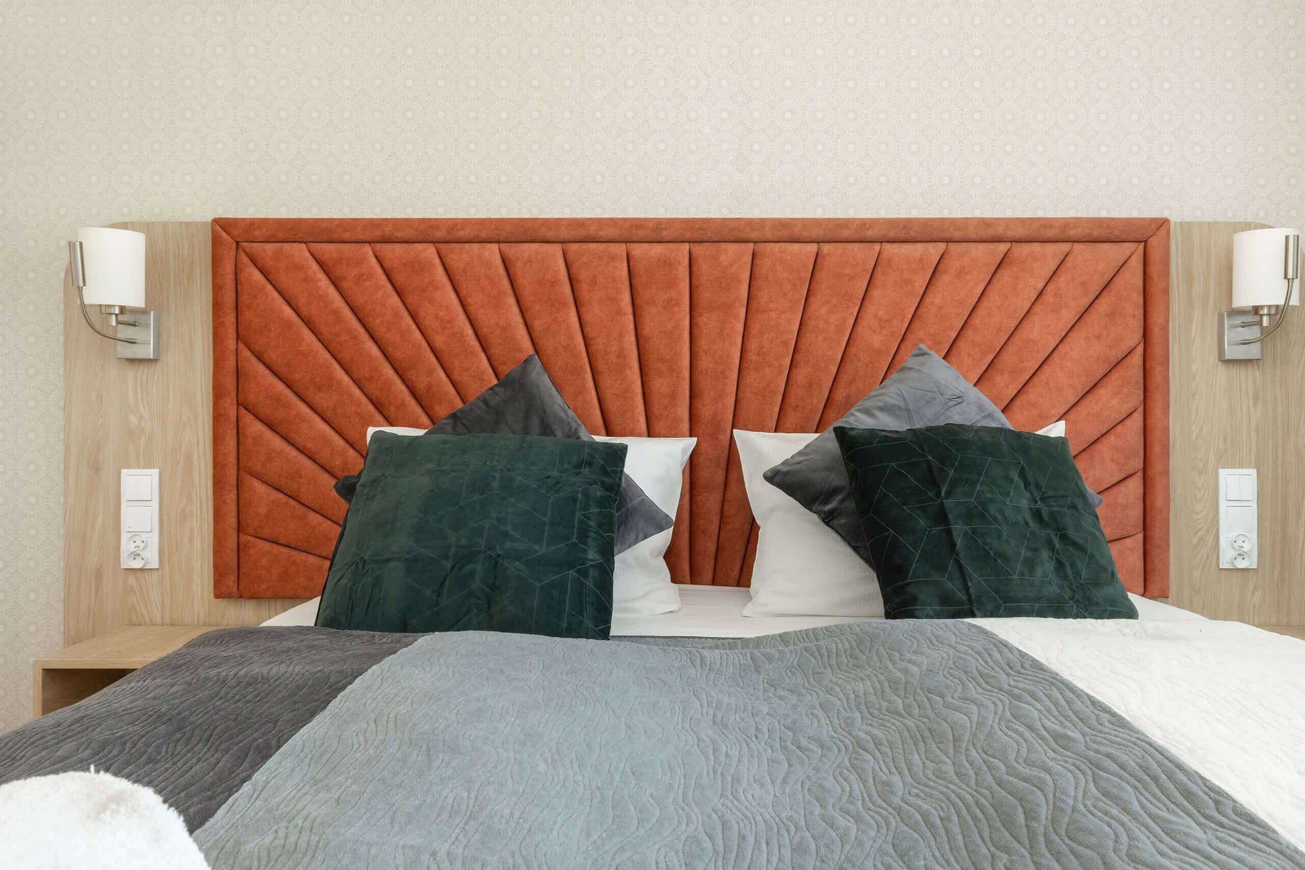 A bed with a tufted headboard, multiple pillows, and bedside lamps.