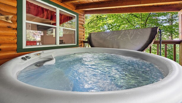 Un jacuzzi en una cabaña de madera con vistas a árboles.