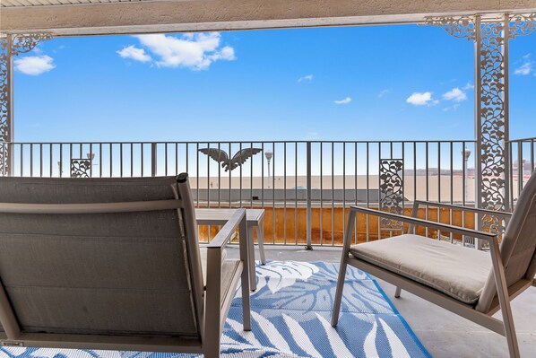 Een balkon met twee stoelen, een tafel en een kamerkleed met dessin.