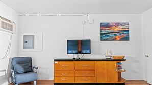 A room with a television, a cabinet, a chair, and a painting on the wall. - 2 Bed/1 Bath on the Boardwalk by the Inlet (Ocean City)