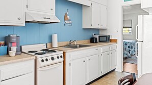 A kitchen with white cabinets, a stove, a microwave, and a blue accent wall. - 2 Bed/1 Bath on the Boardwalk by the Inlet (Ocean City)