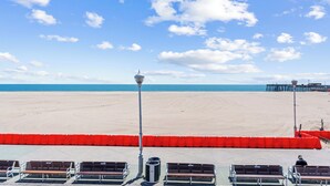 A beach view with benches, a red barrier, and a pier in the distance. - 2 Bed/1 Bath on the Boardwalk by the Inlet (Ocean City)