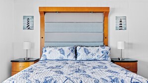 A bed with a blue and white patterned bedspread, wooden headboard, and two bedside tables with lamps. - 2 Bed/1 Bath on the Boardwalk by the Inlet (Ocean City)