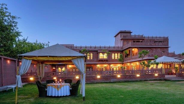 A traditional building with multiple balconies and a dining area with a tent. - TreeHouse Rajbagh (Luni)