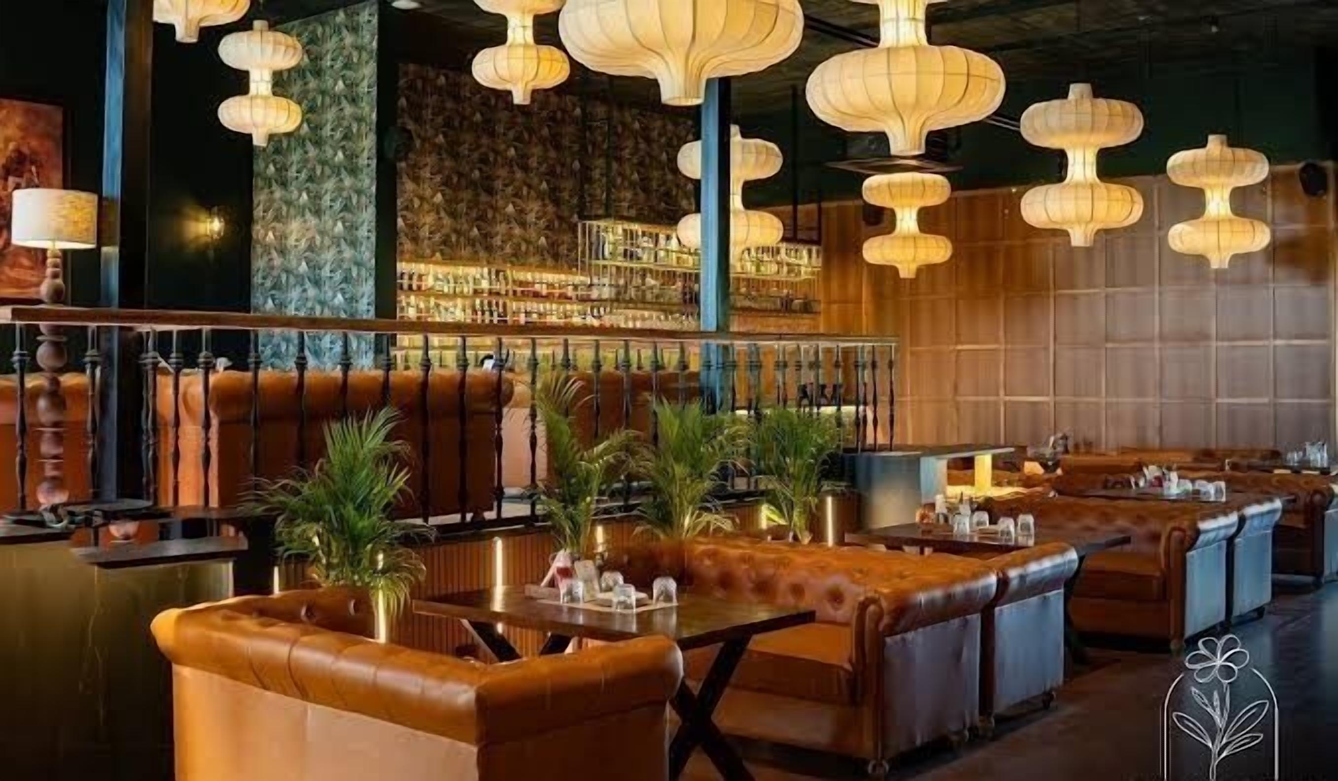 A bar area with leather seating, hanging lamps, and a patterned wall.