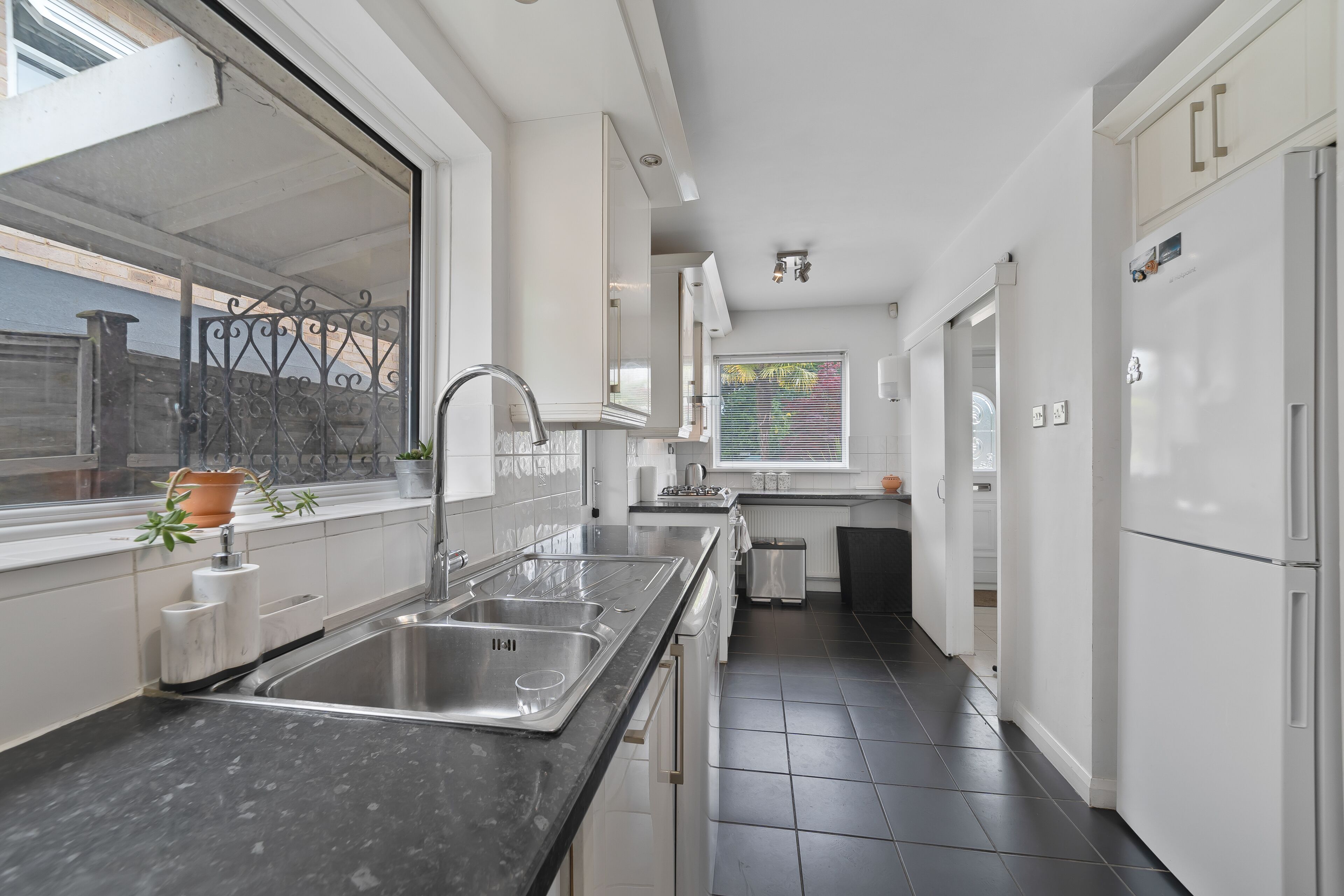 A modern kitchen with a large sink, stainless steel appliances, and a window with blinds.