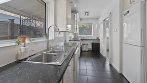 A modern kitchen with a large sink, stainless steel appliances, and a window with blinds. - 3 Bedroom Spacious Bungalow Sunningdale Lodge Ascot Racecourse (Sunningdale)