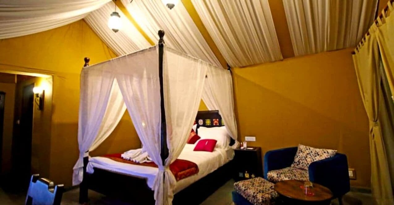 Una habitación con una cama con dosel, una pequeña mesa y una silla.