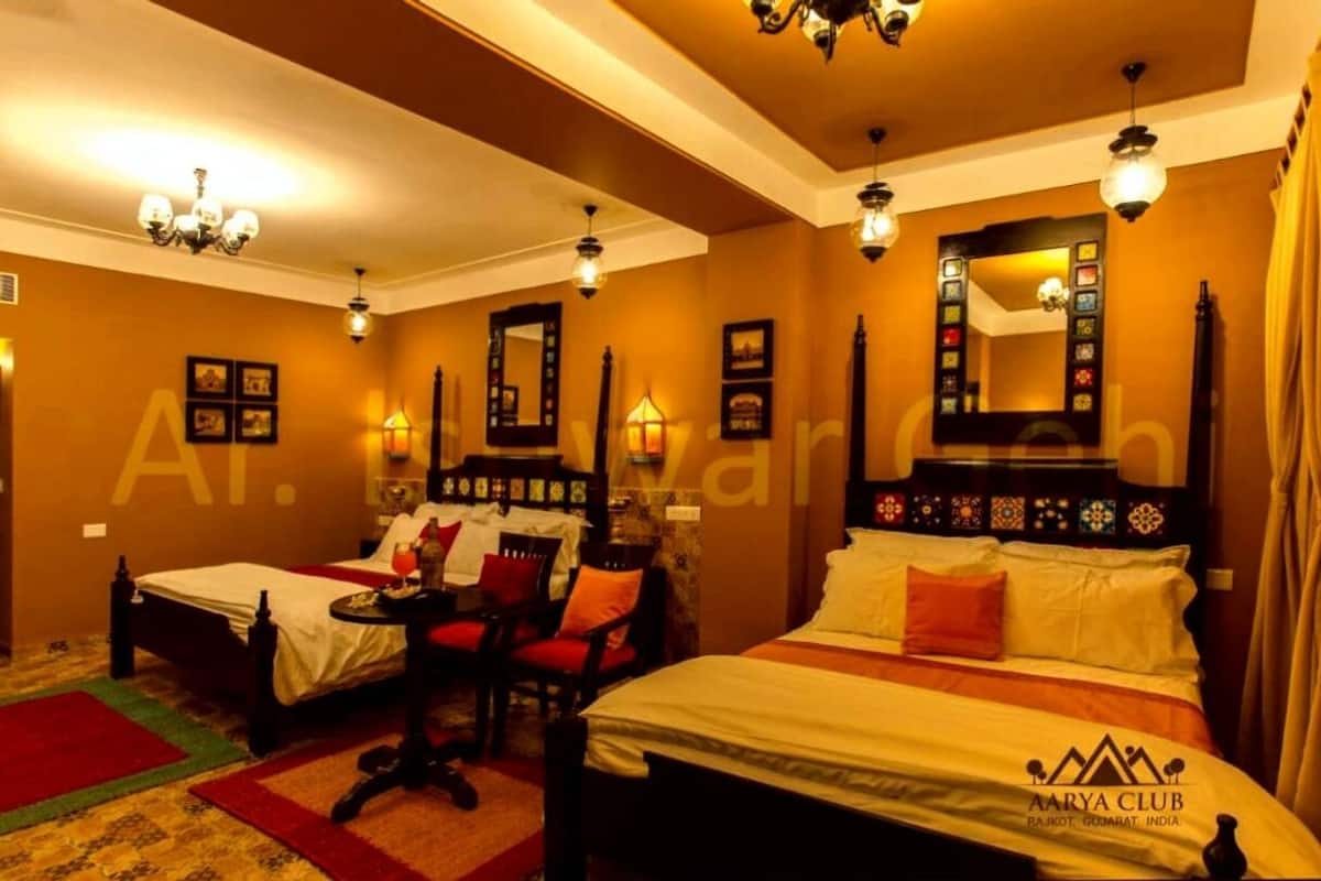 Ein Hotelzimmer mit zwei Betten, einer Sitzecke inklusive Sessel und Tisch sowie einem großen Spiegel an der Kopfteil.