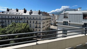 Une vue d’une ville avec ses bâtiments, un ciel dégagé et des montagnes en arrière-plan.