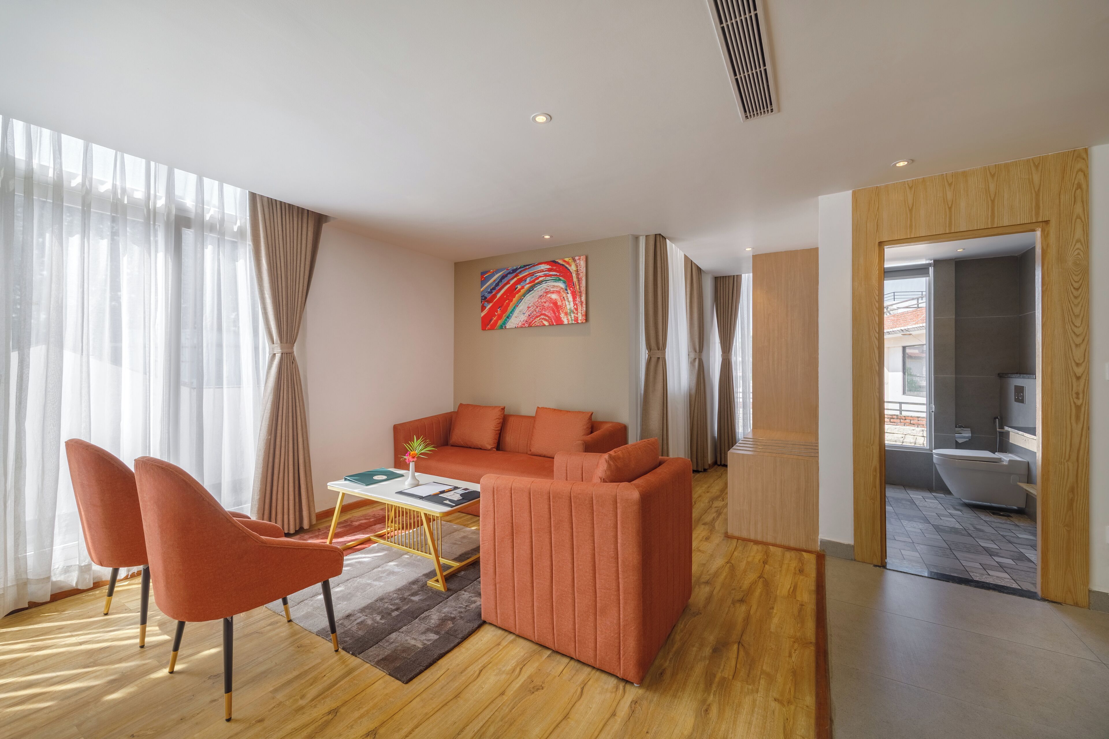 Una sala de estar moderna con un sofá, dos sillones, una mesa de centro y un cuadro en la pared.