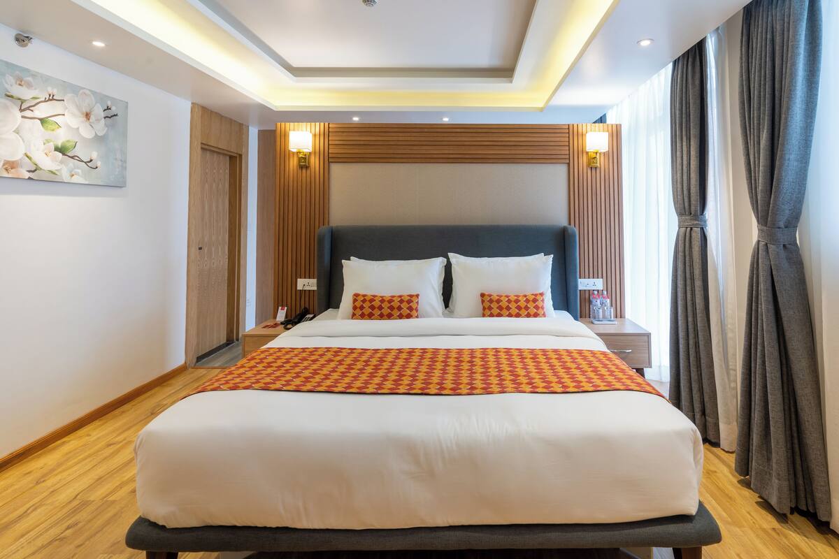 A hotel room with a large bed, wooden paneling on the walls, two bedside tables with lamps, and a painting on the wall.