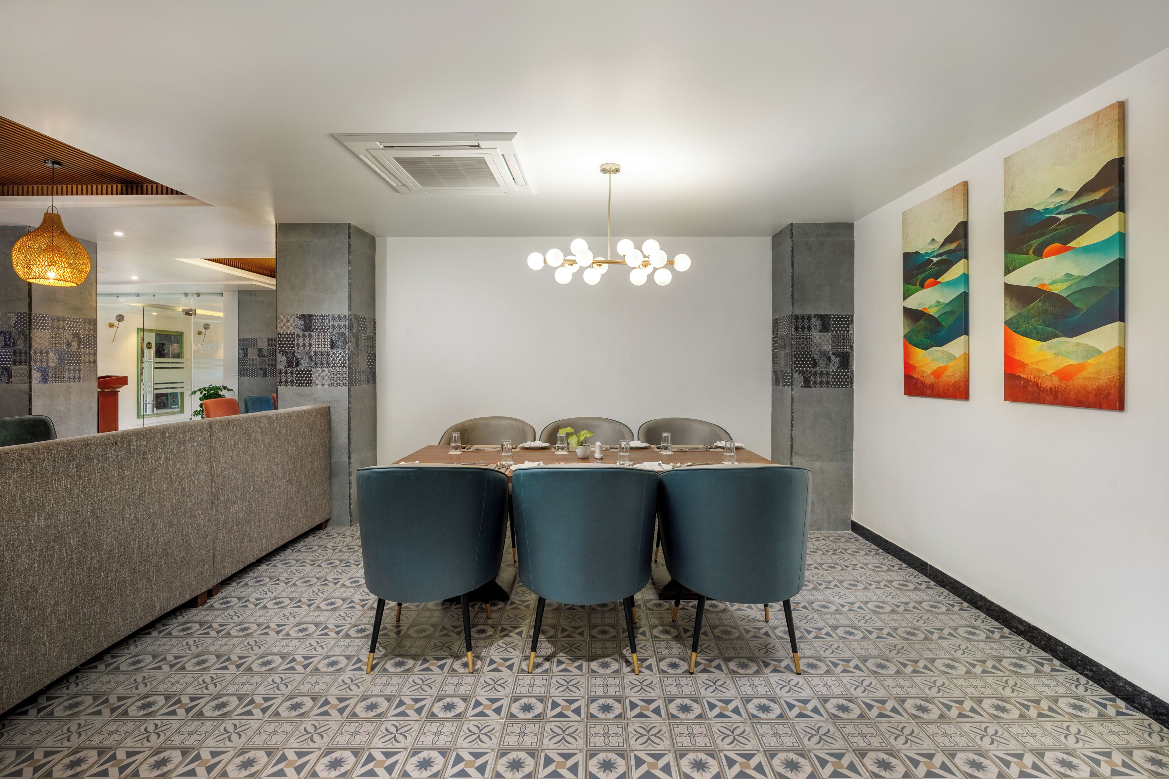 Un espace de salle à manger moderne avec un sol à motifs, une table en bois dressée pour quatre personnes et un lustre original.