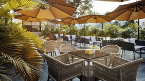 An outdoor patio area with wicker furniture and large umbrellas providing shade. - Hotel Anuttara, Boudha (Kathmandu)