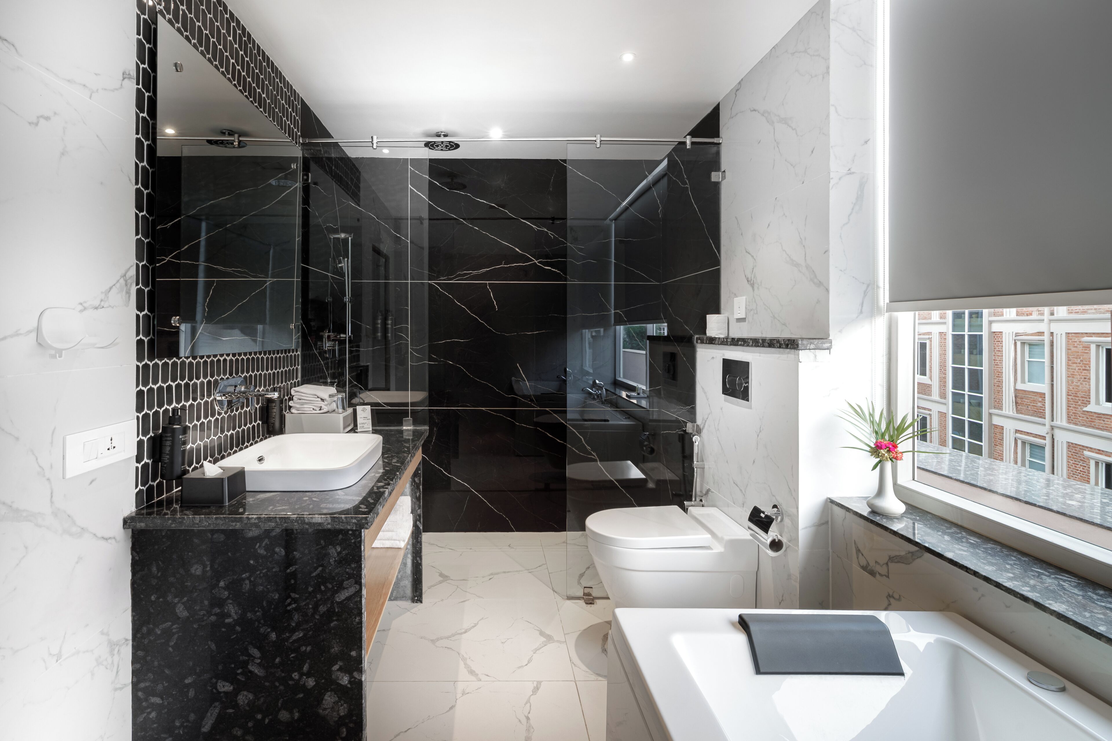 A modern bathroom with a glass-enclosed shower, a white sink, a bathtub, and a toilet.